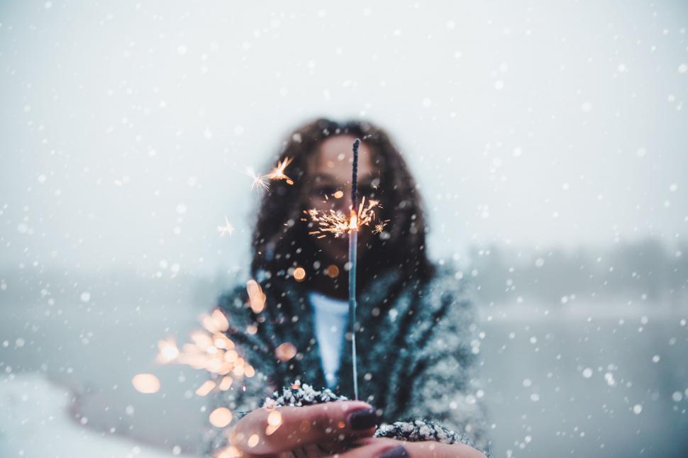 Free Image of Person holding sparkler in snowfall 