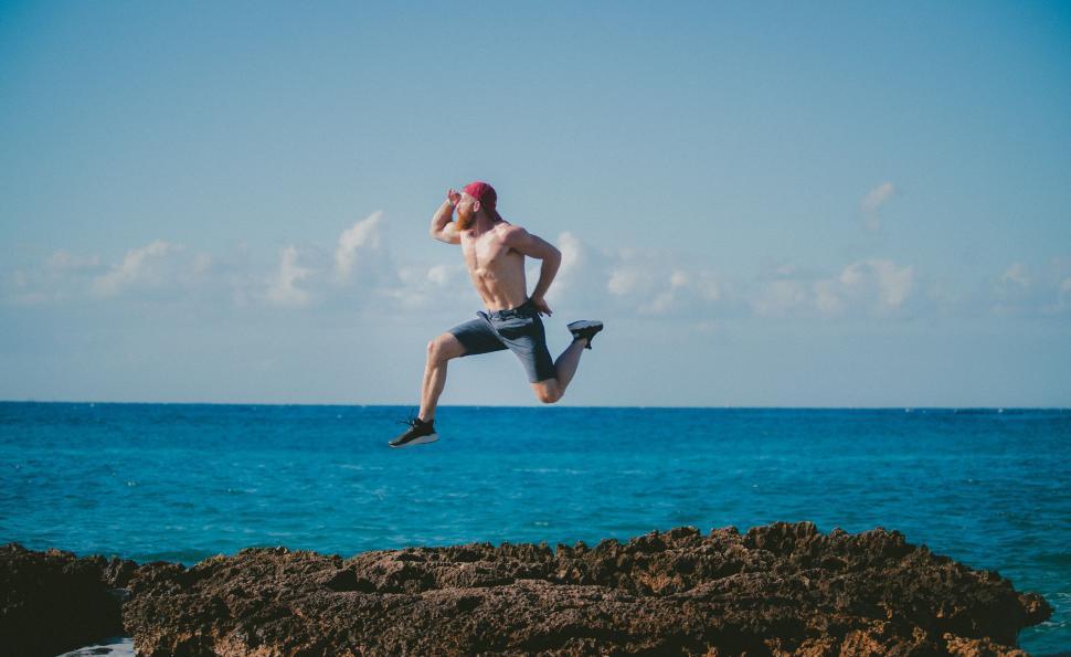 Free Image of Man jumping off a rocky coast into sea 