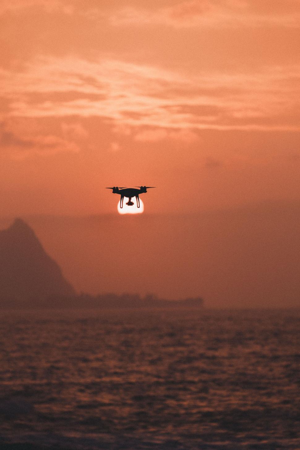 Free Image of Drone silhouette flying at sunset over sea 