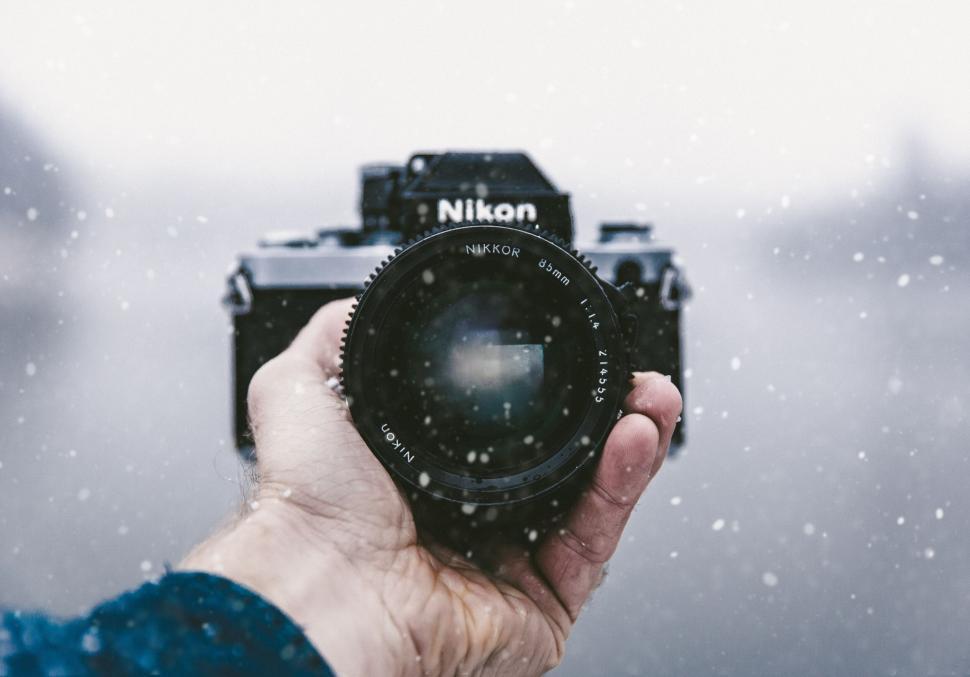 Free Image of Hand holding a Nikon camera in snow 