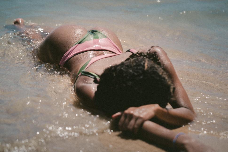 Free Image of Person lying on sandy beach in bikini 