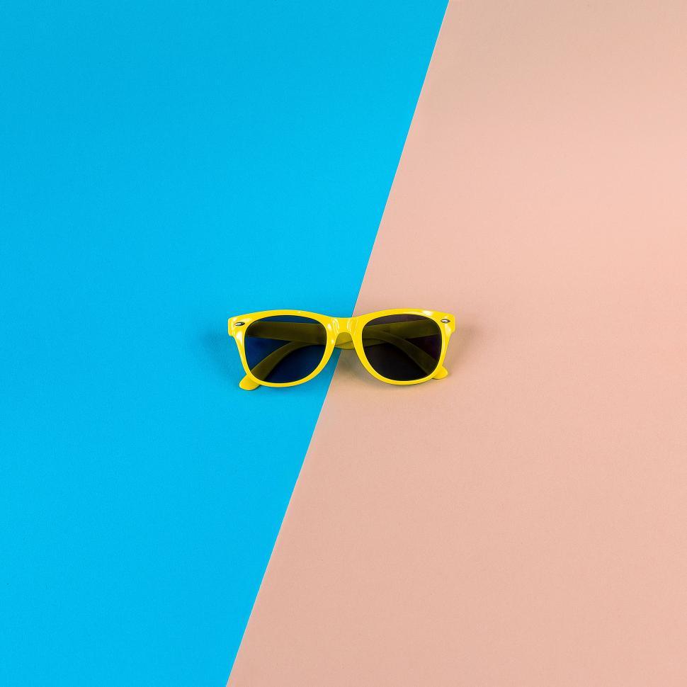 Free Image of Yellow sunglasses on a half-blue half-pink background 