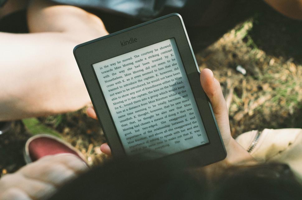 Free Image of Person reading on Kindle outdoors 
