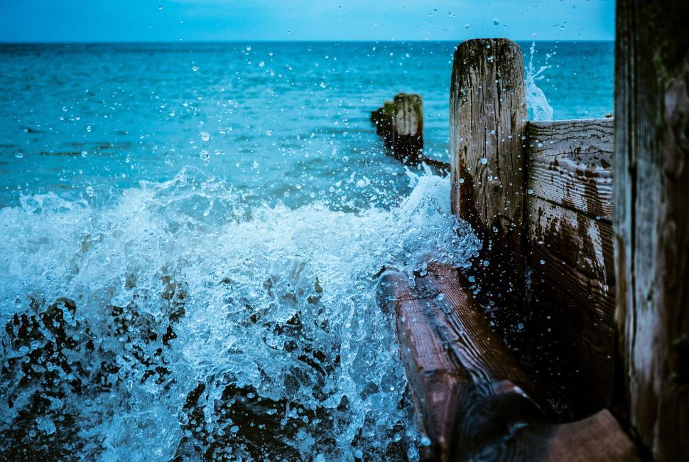 Free Image of Wave splashing against wooden posts 