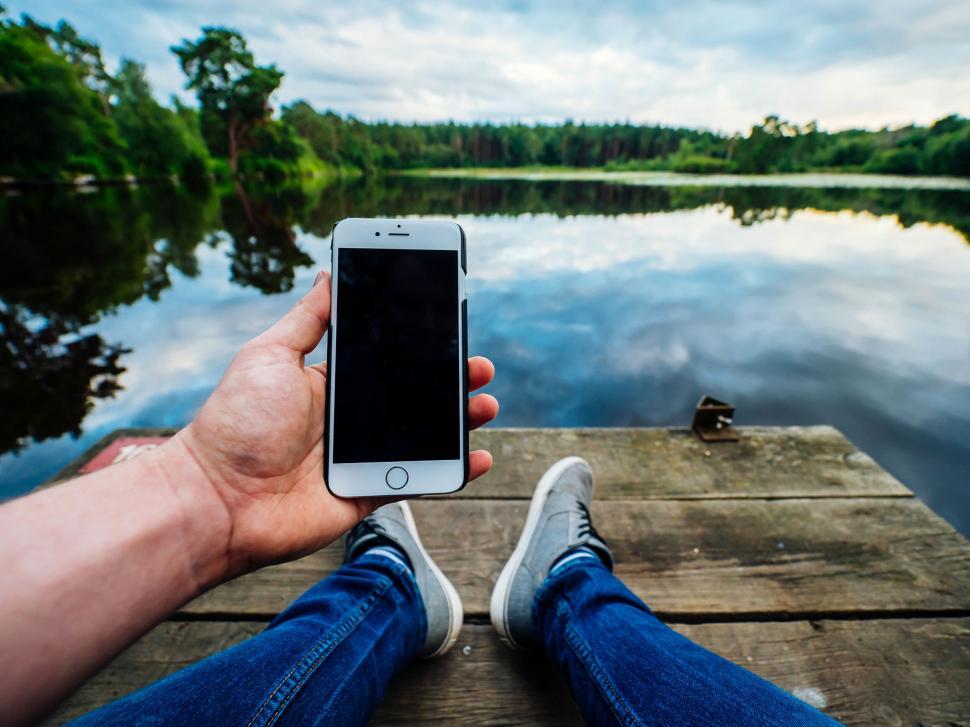 Free Image of Person holding phone sitting on dock 