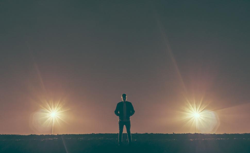 Free Image of Person silhouetted between two lights at dusk 