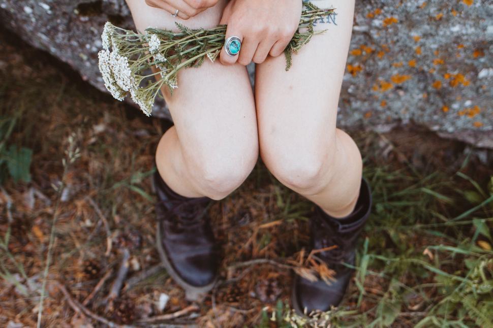 Free Image of Close-up of woman s legs holding wildflowers 