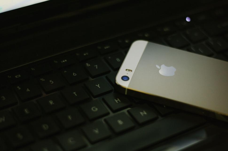 Free Image of Gold smartphone on a keyboard, suggestive lighting 