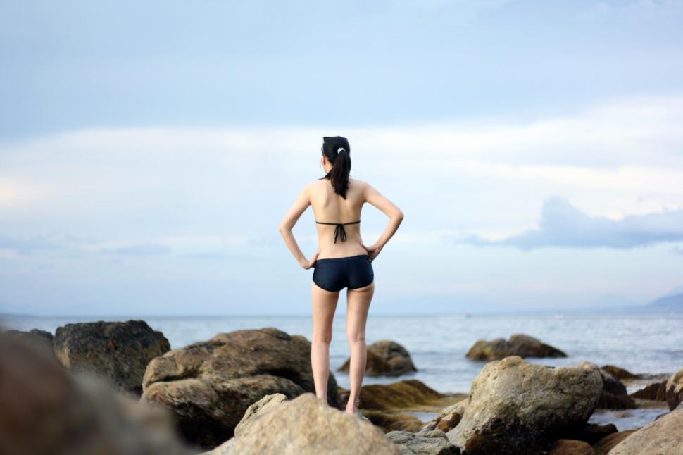 Free Image of Woman standing by the sea looking at horizon 