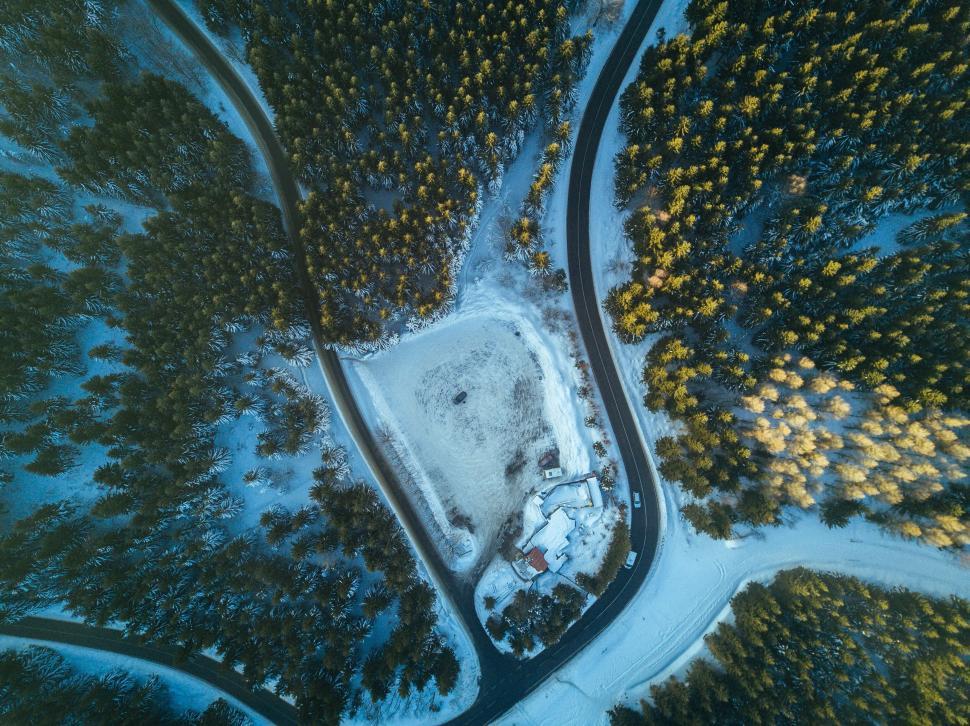 Free Image of Aerial view of snowy forest road and cabin 