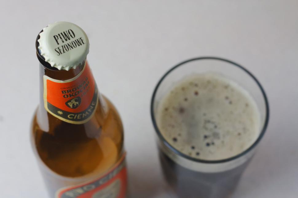 Free Image of Bottle and glass of frothy beer on table 
