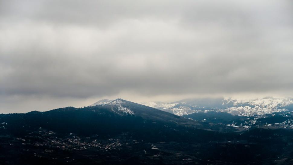 Free Image of Snow-capped mountains under cloudy skies 