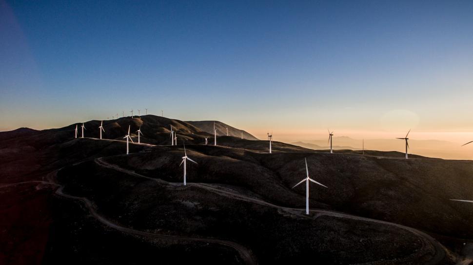 Free Image of Wind turbines on undulating hills at sunset 