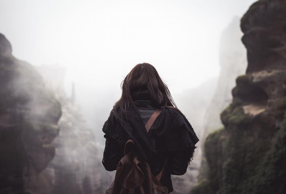Free Image of Person facing misty cliffs with backpack 