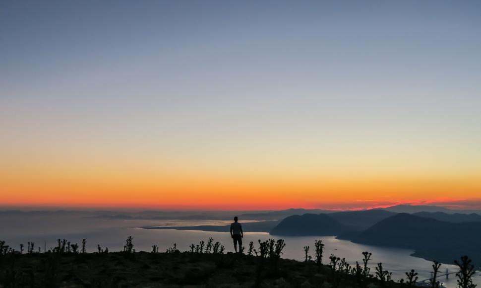 Free Image of Silhouetted person at sunrise over mountains 
