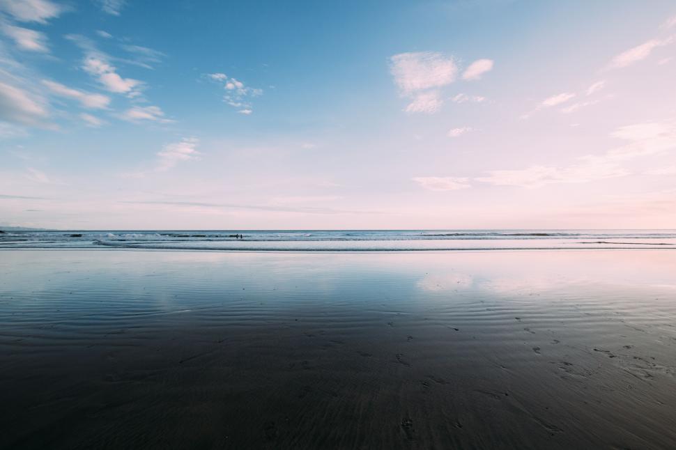 Free Image of Tranquil beach scene with reflective sand 