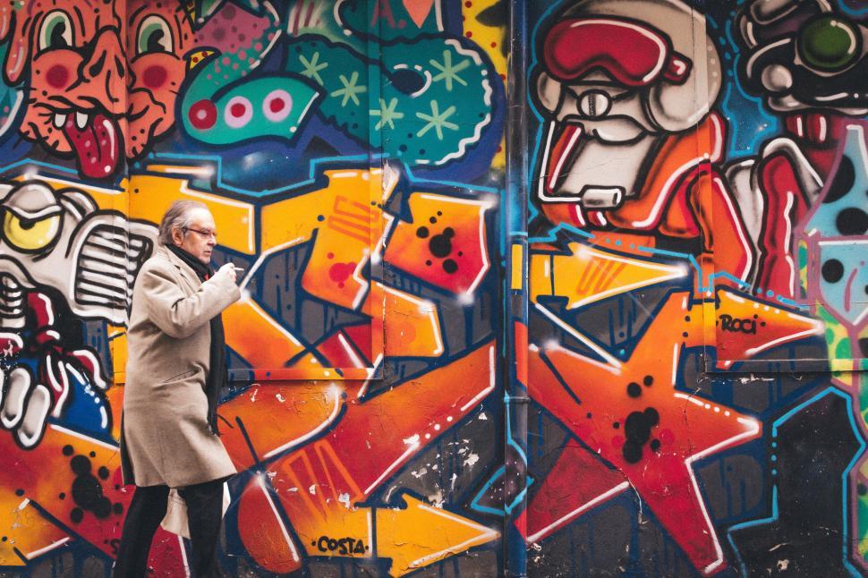 Free Image of Man passing colorful graffiti art on urban wall 