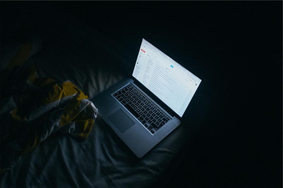 Free Image of Laptop on bed under moody lighting 