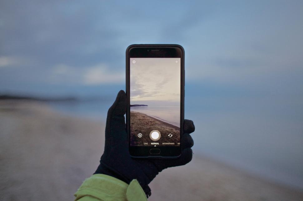 Free Image of Smartphone capturing beach sunset in hand 