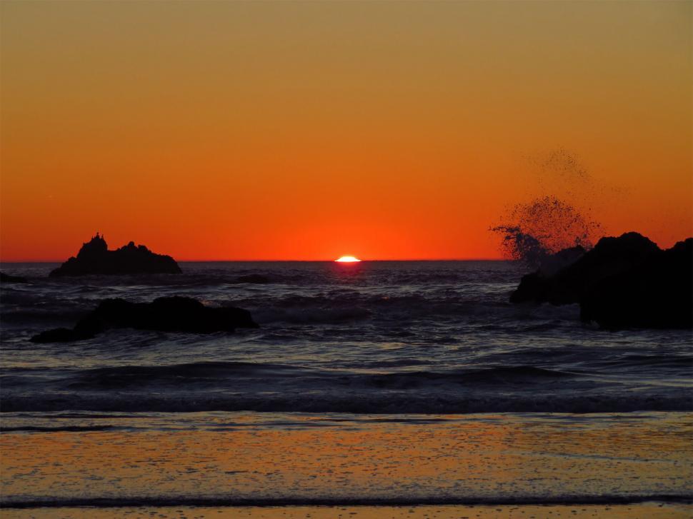 Free Image of Sunset over ocean with rock formations 