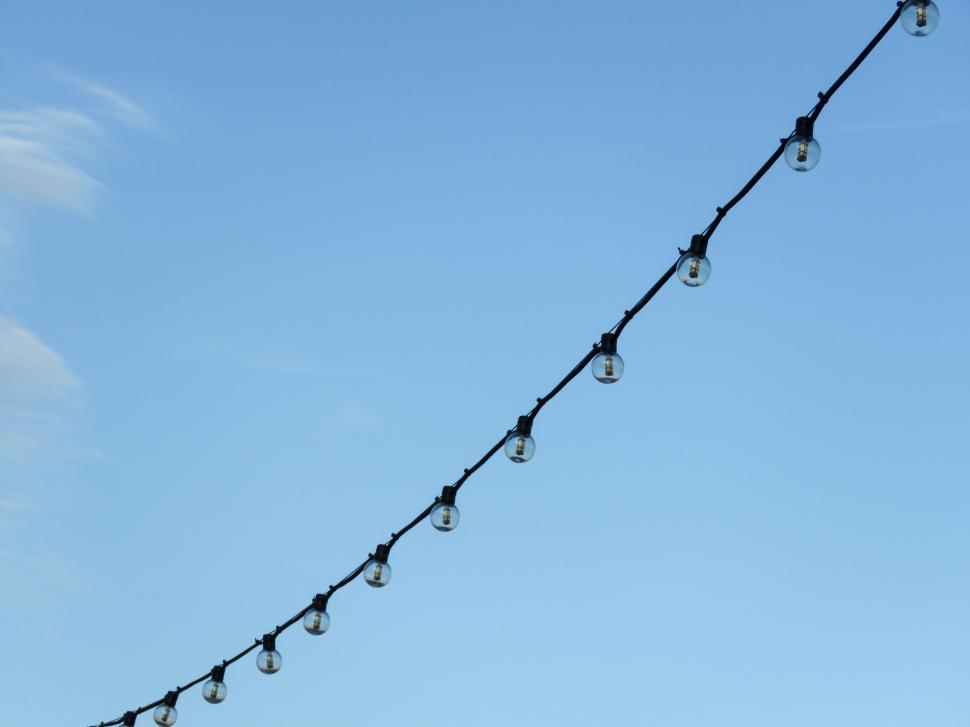 Free Image of String of bulbs against clear blue sky 
