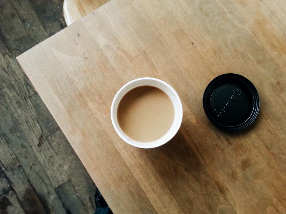 Free Image of Cup of coffee on a wooden table viewed from above 