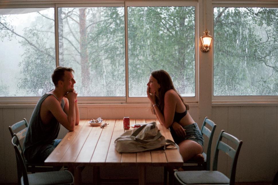 Free Image of Couple dining by window during rain 