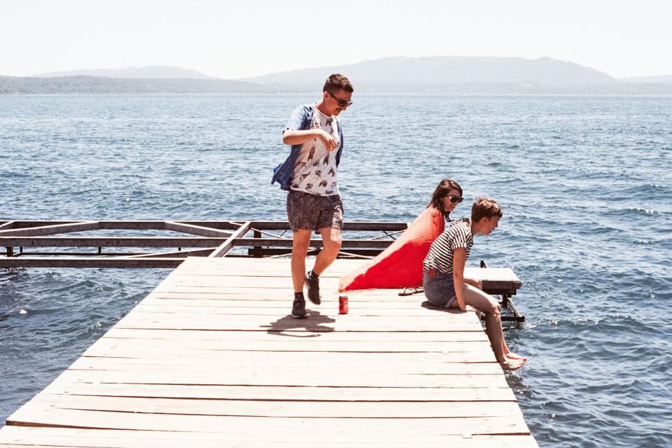 Free Image of People lounging on a wooden pier by the sea 