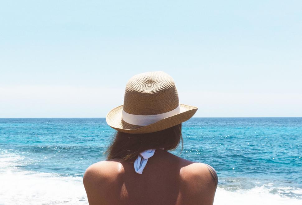 Free Image of Woman facing the sea with straw hat 