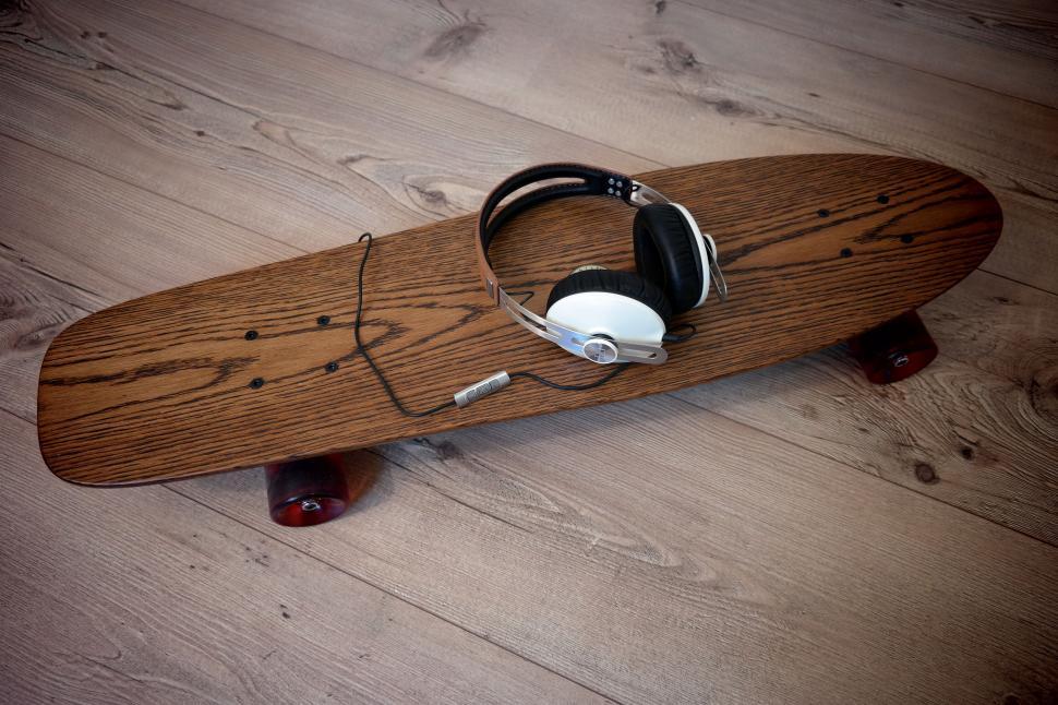 Free Image of Longboard with headphones on wooden floor 