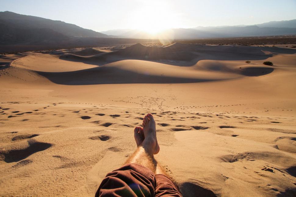 Free Image of Person relaxing in desert dunes at sunset 
