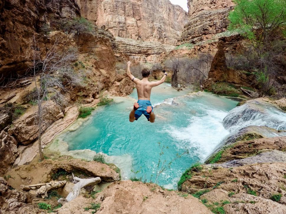 Free Image of Man jumping into a canyon watering hole 