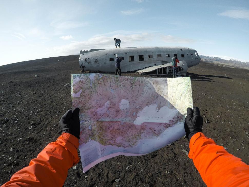 Free Image of Person holding map in front of plane wreck 