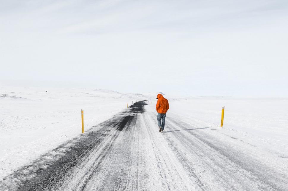 Free Image of Person walking on snowy road in orange jacket 