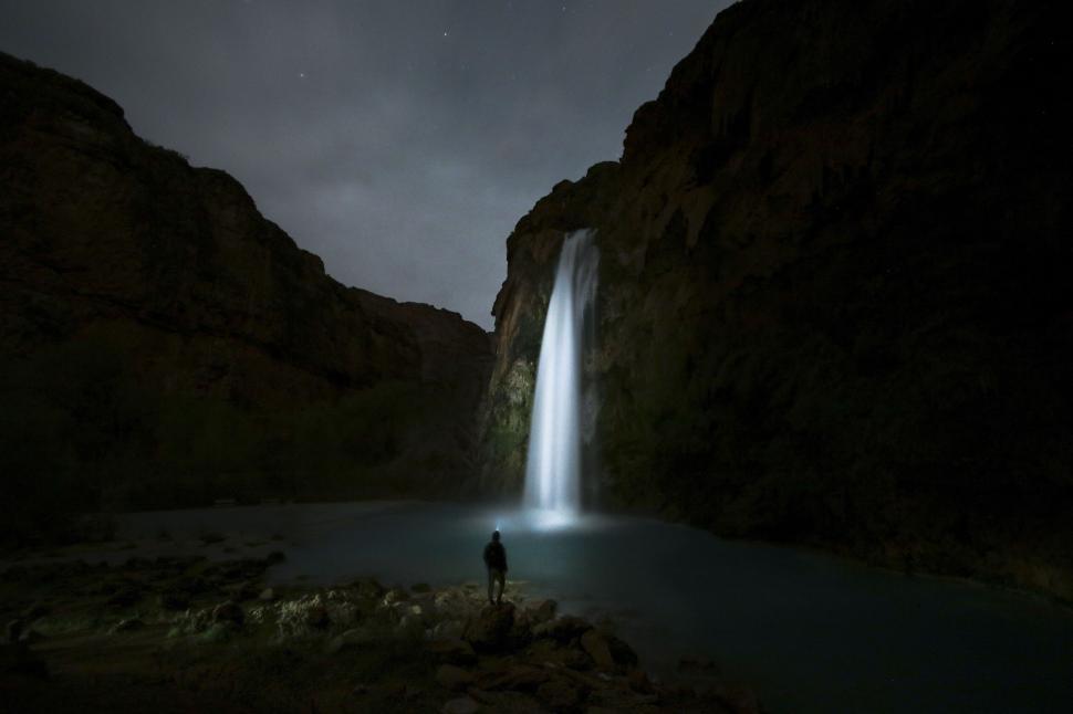 Free Image of Person at night viewing a lit waterfall 