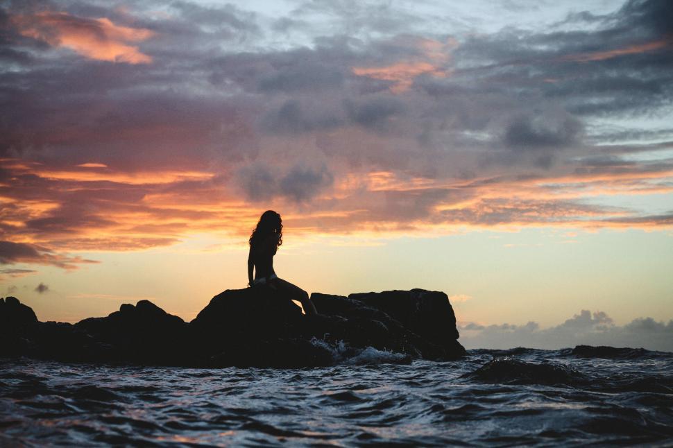 Free Image of Silhouette of a woman on a rock by the sea 