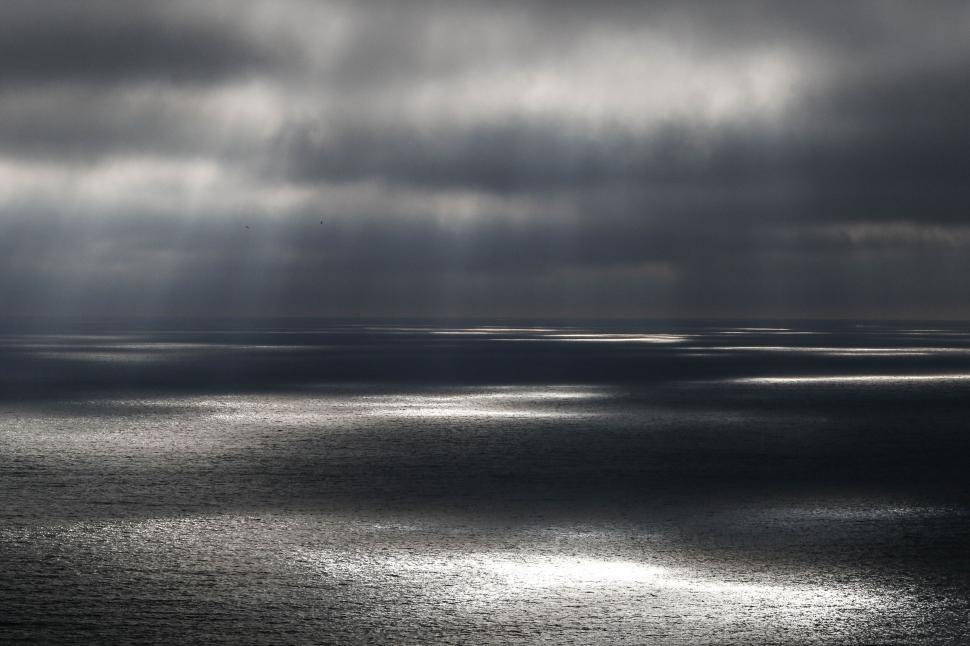 Free Image of Moody ocean scene with sunrays on water 