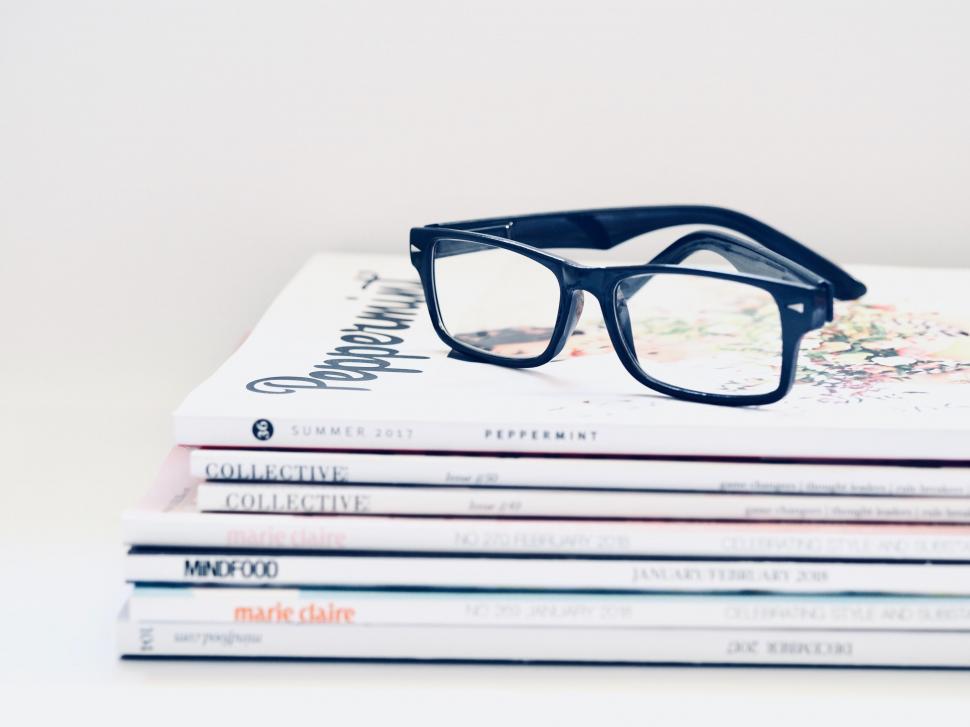Free Image of Stack of fashion magazines with glasses 