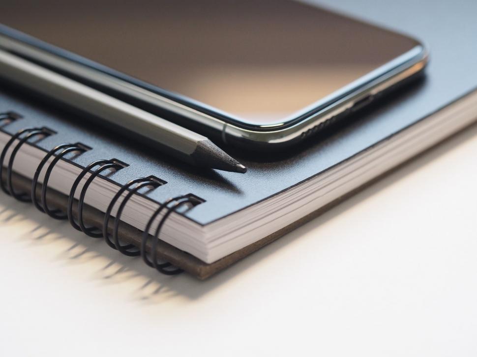 Free Image of Smartphone on top of a spiral notebook 