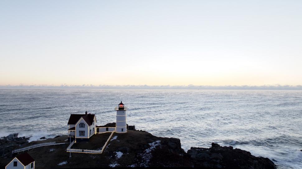 Free Image of Coastal Lighthouse at dawn with waves crashing 