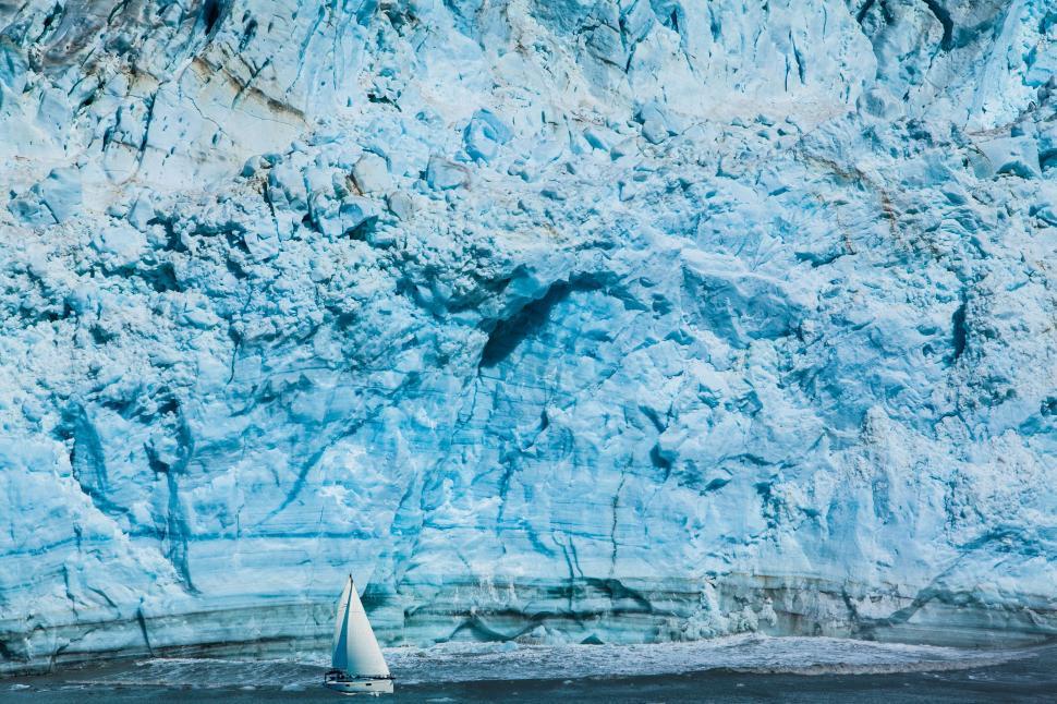 Free Image of Sailboat in front of a massive glacier 
