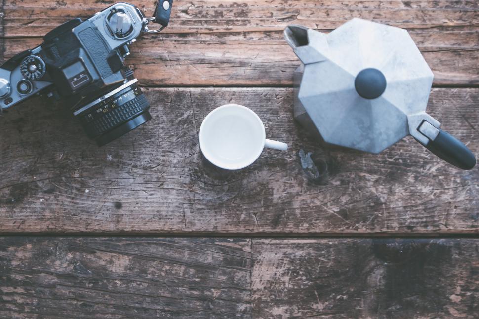 Free Image of Camera, cup, and Moka pot on wooden surface 