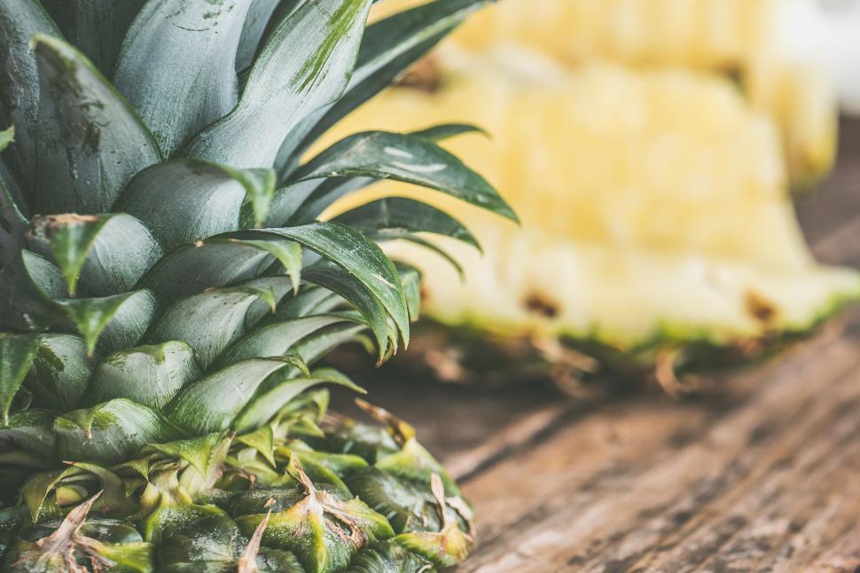 Free Image of Pineapple and slices on a wooden surface 