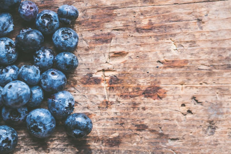 Free Image of Blueberries scattered on rustic wood background 