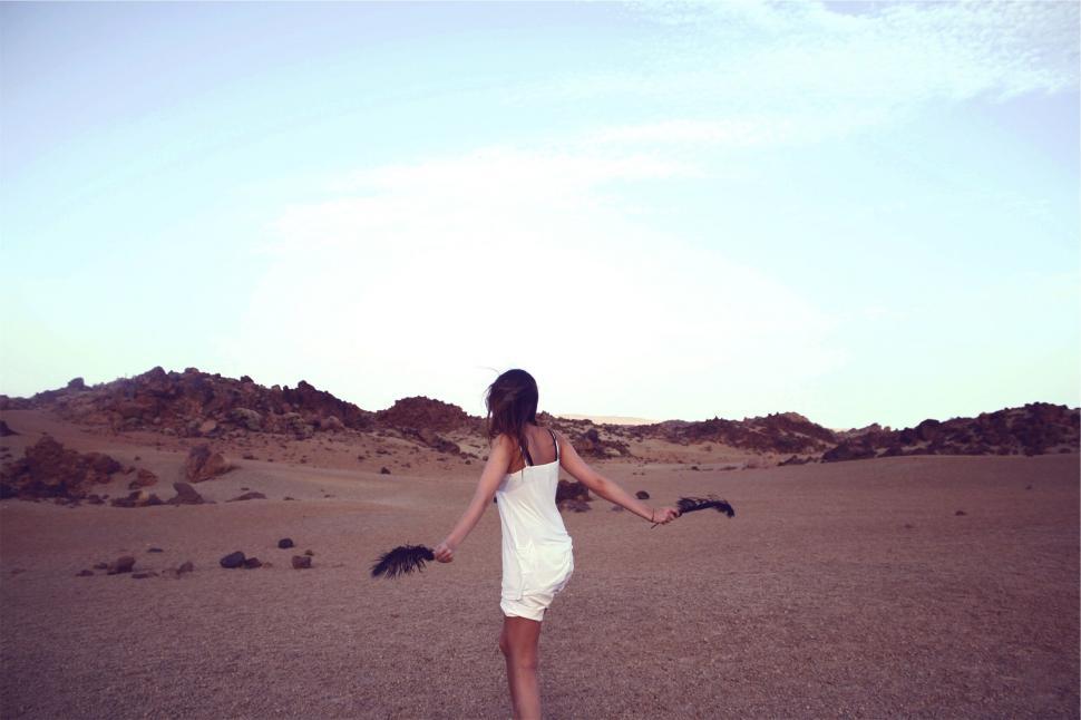 Free Image of Woman in white twirling in a desert landscape 