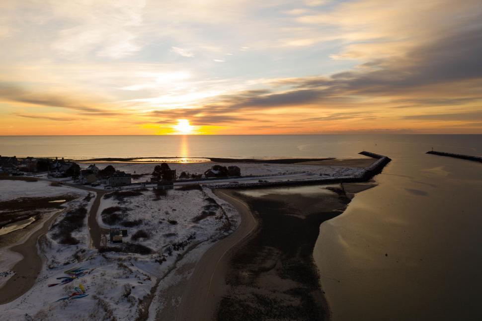 Free Image of Sunset over calm beach with snowy shore and waterway 