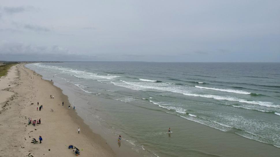 Free Image of Serene beach scene with people enjoying the ocean view 