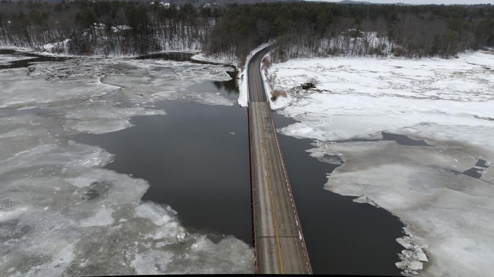 Free Image of A snowy bridge crossing a partly frozen body of water. 