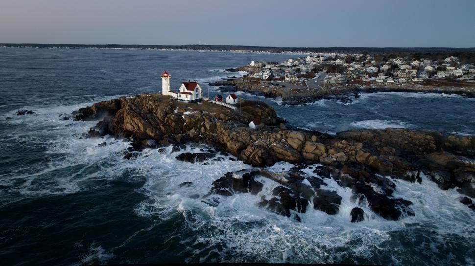 Free Image of Majestic lighthouse on rocky coast with rough waves 
