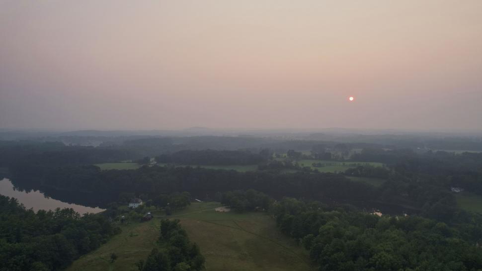 Free Image of Sunset over forested landscape with hazy atmosphere 